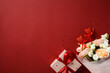 © photoguns - Valentines Day background with a bouquet of roses, a gift box wrapped in white paper with a red ribbon, and red glitter hearts on a red backdrop. Perfect for romantic and festive themes