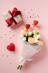 Wall Mural - Valentine's Day bouquet with roses, a gift box with a red ribbon, and heart decorations on a pink background. Perfect for romantic and festive themes