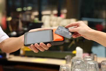 Wall Mural - Woman paying with credit card via terminal in cafe, closeup