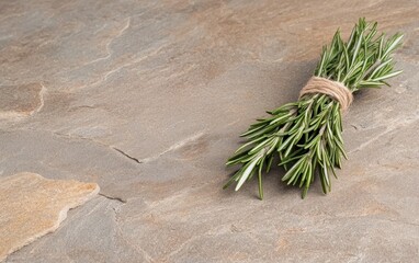 Fresh rosemary tied with twine on a rustic stone background