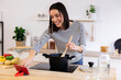 © Xavier Lorenzo - Young happy pretty woman using mobile looking for video recipe tutorial while cooking vegetable vegan soup. Healthy eating habits concept