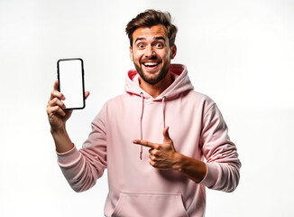 Poster - Handsome man in light pink hoodie presents empty smartphone screen. Man happy, excited. Points at screen. Studio shot. Modern app advertisement. Mobile tech. Trendy style. Great for showing new app