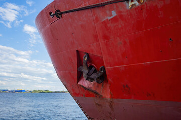 bow with anchor of the sea vessel standing at the berth against the background of blue summer sky