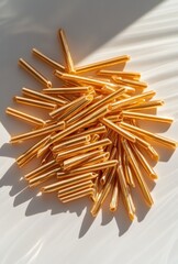 Poster - A Pile of Golden Metal Tubes on a Light Surface Creating a Bright and Modern Aesthetic Perfect for Various Creative Projects and Design Concepts