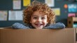© Dai - Close-up image of a laughing child leaning out of a cardboard box, with classroom bulletin boards in the background, isolated on a light gray background