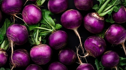 Wall Mural - Vibrant purple turnips with lush green leaves on black background