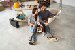 © Pixel-Shot - Young couple with plan and Beagle dog sitting during repair in their new house