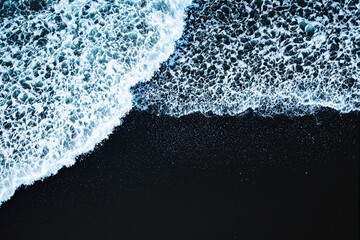 Poster - Ocean waves meeting dark sand on a beach, captured from above, illustrating nature's contrast and beauty.