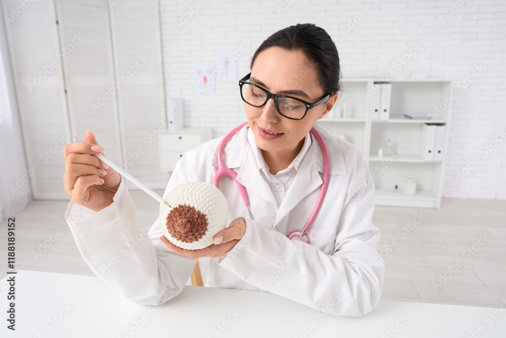 Female doctor with knitted breast model at table in clinic