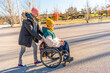 © unai - Man pushing friend in wheelchair enjoying sunny day in park