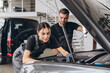 © anatoliycherkas - Trying to identify the source of the problem. Two mechanics man and woman working together at open hood on a car in an auto repair shop.