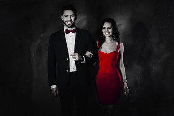 Aufkleber - Portrait of positive cheerful lady with hairstyle curls and positive man with bristle in blue tuxedo famous lovely couple looking at camera isolated on dark grey background with shadow