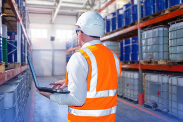 Poster - Man with laptop in fuel warehouse. Storekeeper with computer among racks barrels. Warehouse contractor at work. Man manager oil distribution center. Storekeeper in orange vest in warehouse hangar