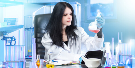 Poster - Woman is engaged in biotechnology. Girl biologist sits at laboratory table. Test tube in hands of researcher. Experiment in field of biotechnology. Woman in white coat works in laboratory.