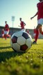 © val - A close-up of a soccer ball on the field with players in action, capturing the essence of the game. Perfect for sports-related projects and promotions.