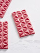 © Food Images - Bright pink chocolate bars with a geometric pattern are elegantly displayed on a smooth, light surface. Their vibrant color and unique shape create an appealing visual treat