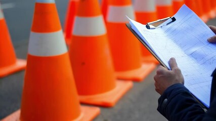 Poster - Experienced supervisor meticulously reviewing comprehensive traffic management plan near strategically placed orange safety cones at active construction site