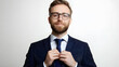 © mahamad - A portrait of a handsome businessman in a suit and glasses, tying his tie against a white background.