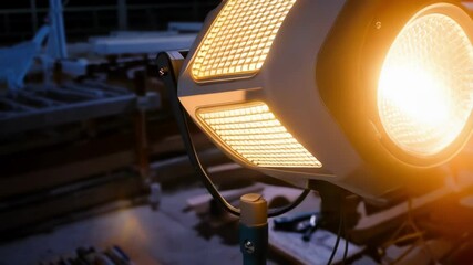 Poster - Bright construction light illuminating a dimly lit worksite, creating a warm glow and enhancing visibility for workers during nighttime operations