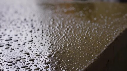 Aufkleber - Multiple views of glistening water droplets resting on the smooth surface of a concrete slab, reflecting light and creating a textured pattern
