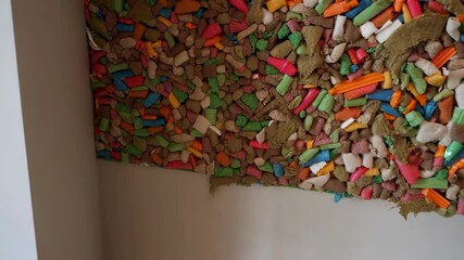Poster - Multicolored recycled insulation material, composed of various shapes and sizes, fills a wall cavity, showcasing sustainable building practices