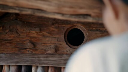Aufkleber - Architect wearing a cream colored sweater and a black cap is inspecting a perfectly circular smoke hole in the darkened wooden ceiling of a traditional dwelling
