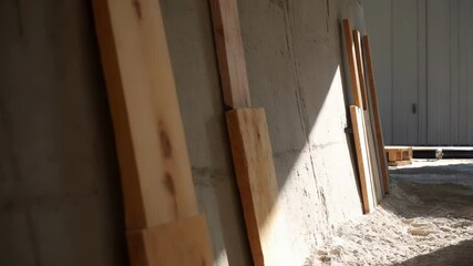 Aufkleber - Wooden formwork leaning against hardened concrete wall, bathed in warm sunlight, resting on sandy ground at active construction site with architectural details emerging