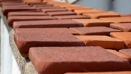 Aufkleber - Multiple terracotta tiles are drying on a roof edge, showcasing varying shades of red and orange, possibly due to the drying process or inherent color variations in the material
