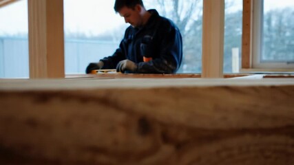 Aufkleber - Skilled construction worker carefully measuring wooden planks at job site, precision determining dimensions for upcoming wall or floor framing in residential building project