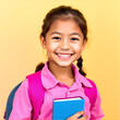 © Colton - A happy hispanic or latino schoolgirl with a book and backpack, dressed in a shirt, smiles warmly against a yellow background, embodying the positive spirit of school and learning