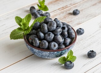 Wall Mural - A bowl of blueberries with green leaves on top