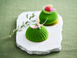 © Food Images - Two beautifully crafted green desserts sit on a white marble platter, decorated with fresh fruits and delicate garnishes. The desserts showcase rich textures and vibrant colors