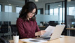 © Lightning - Serious Businesswoman Reviewing Paperwork at Desk