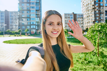 Wall Mural - Selfie portrait smiling student teenager girl looking at webcam outdoor summer city