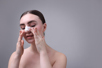 Wall Mural - Woman with medical bandage on her nose after plastic surgery operation against grey background, space for text