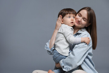 Canvas Print - Mother hugging her little son on grey background. Space for text