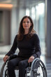 © tynza - Professional woman sitting in a wheelchair in a sleek modern office.