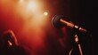 © BerkahStock - Close-up of a microphone on a stand under warm stage lights, slightly blurred background.