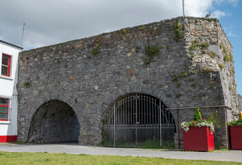 View of the Spanish Arch in Galway, Ireland, showcasing its stone arches and weathered facade under a partly cloudy sky, reflecting the city's rich heritage and medieval architecture