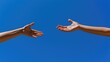 © grooveisintheheart - A helping hand. Two arms. Care and support. Two hands reaching towards each other set against a clear blue sky background. A hand of hope. Gesture. Connection