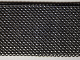 Aufkleber - A close up of a black metal band with a pattern of small squares