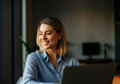 © Rizka - Smiling Woman Working on Laptop in Modern Office