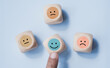 © LAONG - Hand choose wood cube with smile icon, World mental health day or feedback rating concept, Positive customer review, Wood cube with emotion face icon on pastel blue background