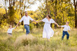 © Austockphoto - Family of four walking together through lush field in golden afternoon light
