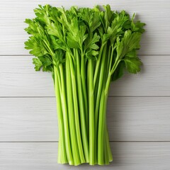 Wall Mural - Fresh celery stalks arranged on a wooden surface in natural light