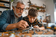 © TATIANA Z - Grandfather and grandson building a model airplane together at a workbench, sharing quality time, focus, and creativity