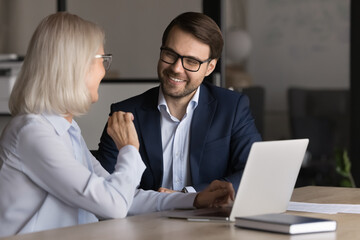 Wall Mural - Pleasant, friendly conversation between two workmates at workplace. Smiling millennial male employee listening speech of woman colleague, managers selling services, convincing, engaged in negotiations