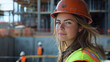 © Olena - A woman in a hard hat and safety vest, confidently working on a construction site, overseeing the progress of a building project
