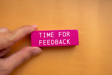 Wall Mural - Time for feedback message written on pink wooden block with orange background. Conceptual time for feedback symbol. Copy space.