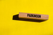 © Emre Akkoyun - Parkinson message written on wooden block on yellow background. Conceptual parkinson symbol. Copy space.
